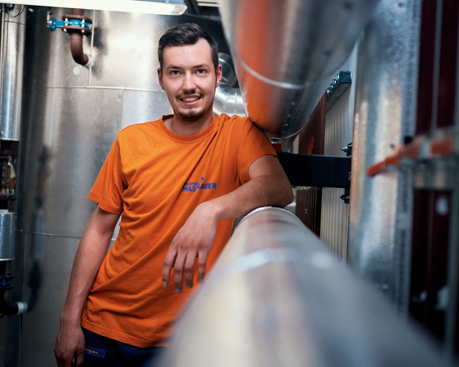 Installateur von Hasenauer Anlagenbau lehnt auf einem Lüftungsschacht