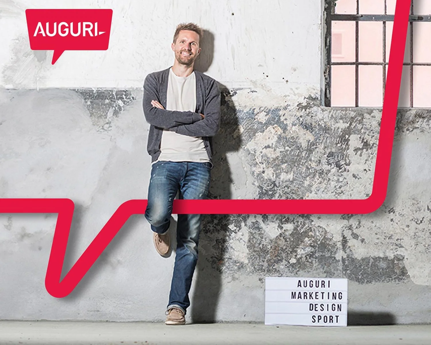 Foto von Florian Lhotka vor einer grauen Wand mit einem Auguri Schild