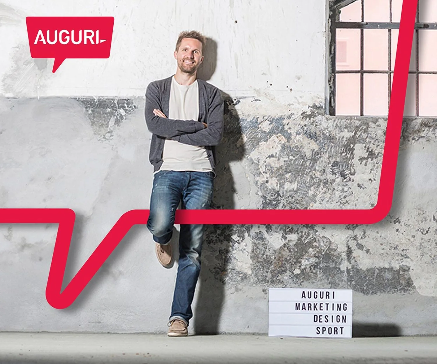 Foto von Florian Lhotka vor einer grauen Wand mit einem Auguri Schild