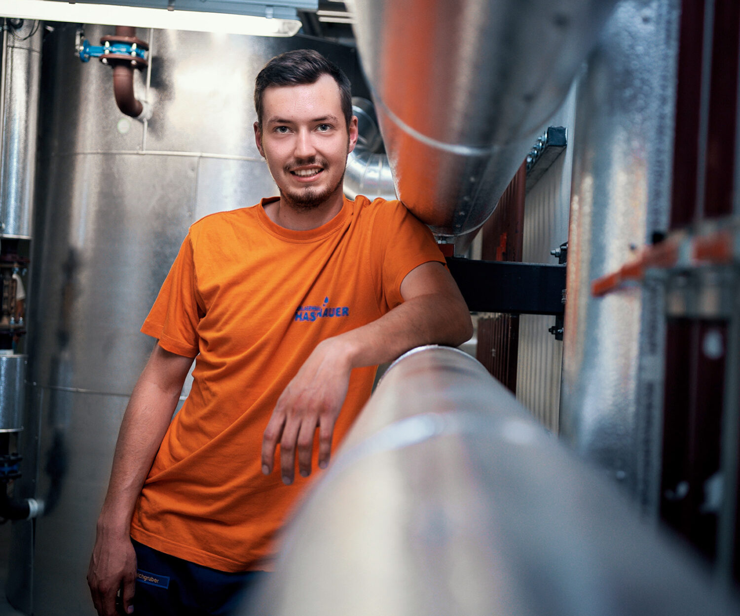 Installateur von Hasenauer Anlagenbau lehnt auf einem Lüftungsschacht