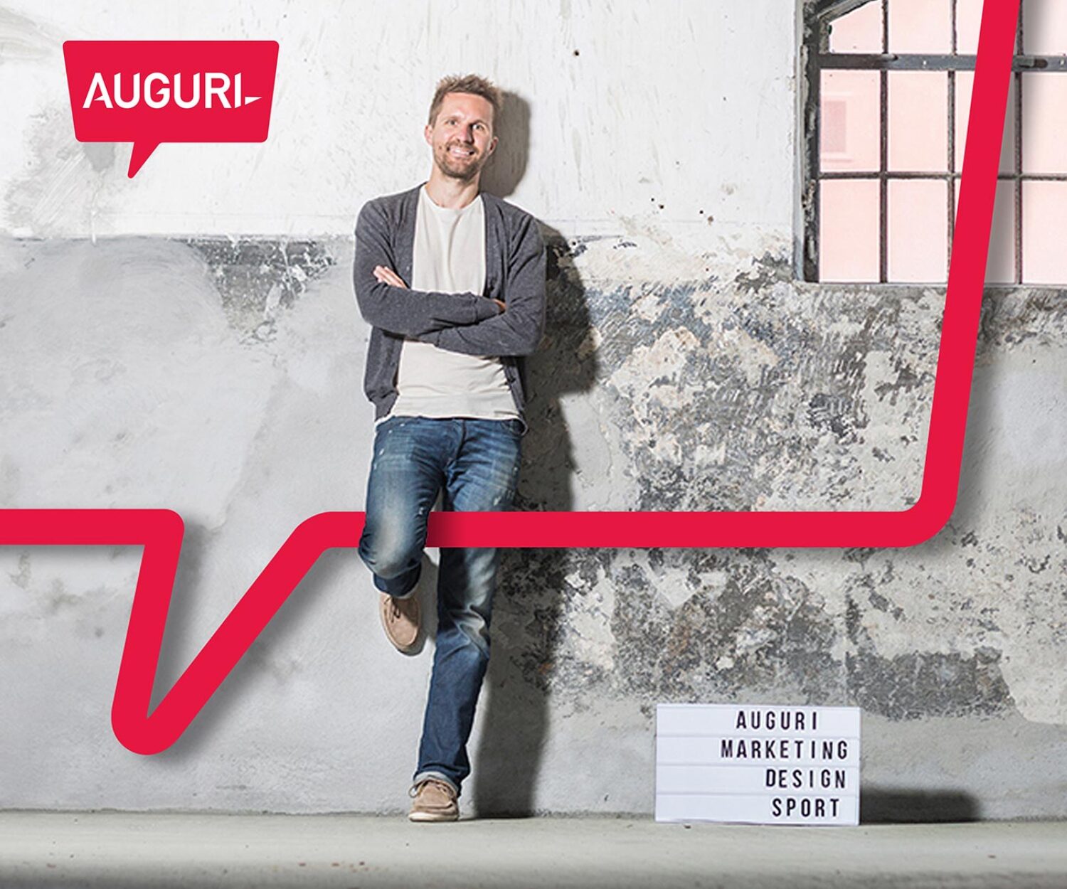 Foto von Florian Lhotka vor einer grauen Wand mit einem Auguri Schild